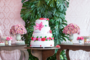 Wedding cake decorated with colorful flowers and edible green leaves