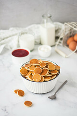 mini pancakes in a deep bowl with strawberry jam on the table on a light background