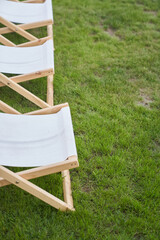 Part of a lightweight folding chair for outdoor recreation. An empty white wooden chaise longue on...