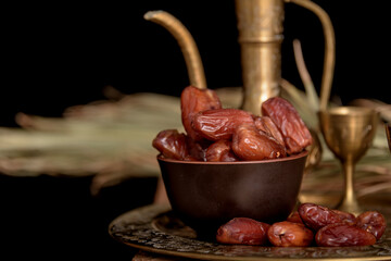 Ramadan concept. Dates closeup in the foreground. Ramadan Lantern on a wooden table. Textured black wall background.