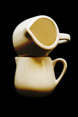 Two creme jugs on a black background