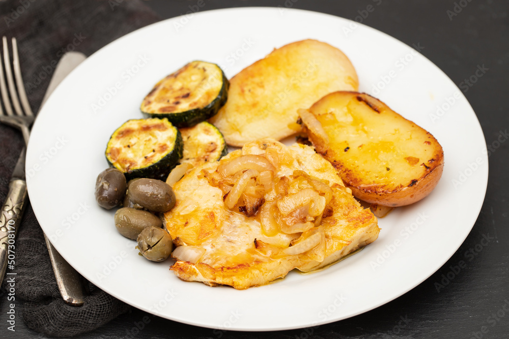 Sticker fried meat with potato, courgette and olives on the plate