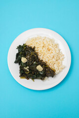 fried spinach with garlic and boiled rice on plate