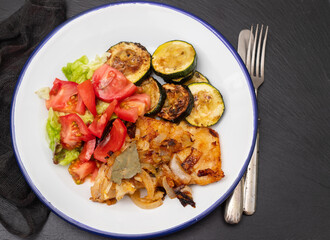 fried meat with courgette and fresh salad on the plate