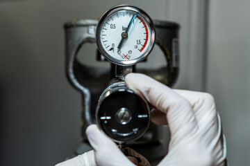 Close up of a hand in gloves adjusting a barometer of a nitrogen cylinder or compressed air - obrazy, fototapety, plakaty