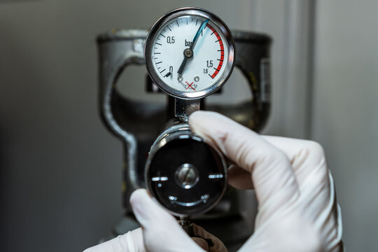 Close up of a hand in gloves adjusting a barometer of a nitrogen cylinder or compressed air
