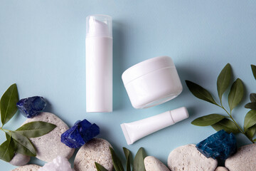 Mockup for cosmetics brand. White cosmetic jars on a blue background, surrounded by natural...