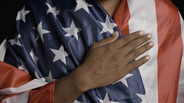 Young man praying by wearing us flag by placing hand on heart - concept of contemplation and freedom.