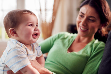 Loving Mother Playing With Baby Son Sitting On Floor At Home