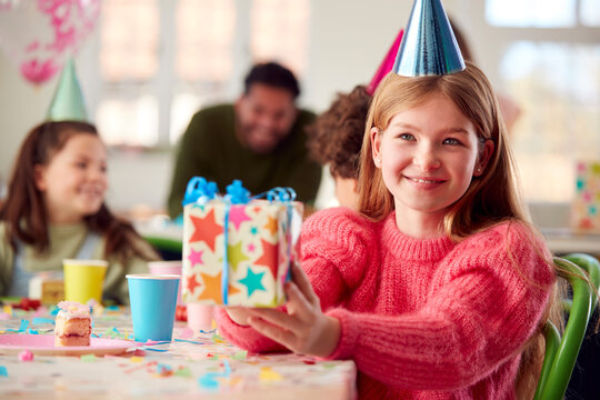 Girl Giving Gift At Birthday Party With Friends And Parents At Home