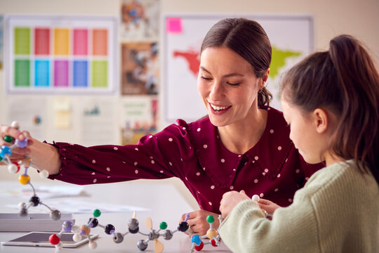 Teacher And Female Student In School Science Class Studying Molecular Model