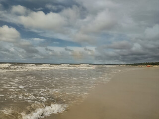 Linda praia de areias escuras sob céu azul com muitas nuvens, localizada em São Luis, Maranhão, Brasil. - obrazy, fototapety, plakaty