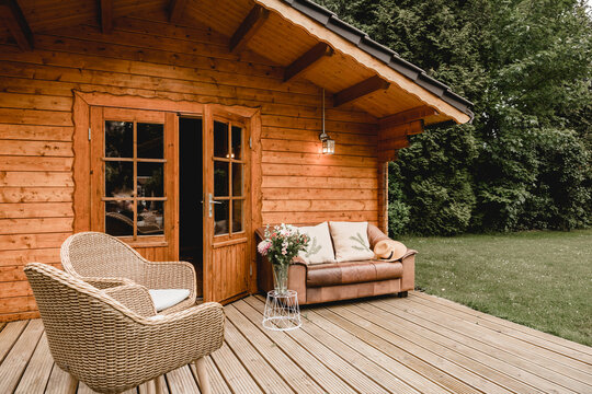 Leather sofa on a terrace outside next to a wooden house. Wooden garden house with outdoor seating. Relaxation in the garden. wooden hut