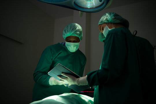 The doctor is discussing the case with a tablet. Before going to surgery on the real patient