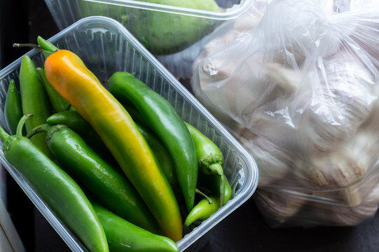 green hot pepper pods and a plastic bag with garlic