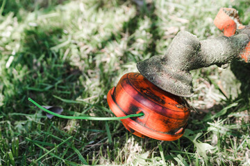Orange trimmer on a background of green grass close up