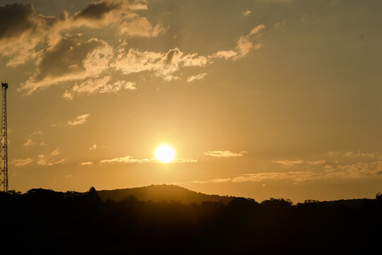 Pôr do sol entre montanhas e céu limpo com nuvens, visto em sítio localizado em Juatuba, Minas Gerais, Brasil.