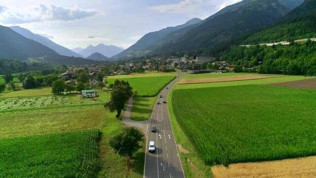 Cars riding on a mountain road near ripe fields