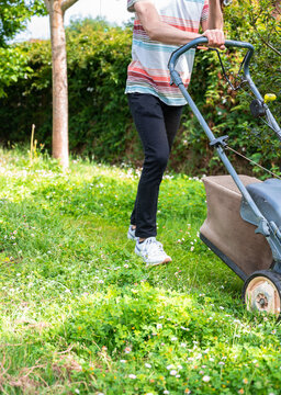 Faceless Young Boy Mowing The Lawn