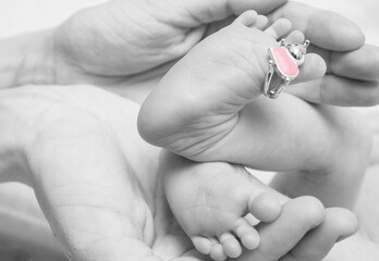 Parent holding in the hands feet of newborn baby. Closeup photo
