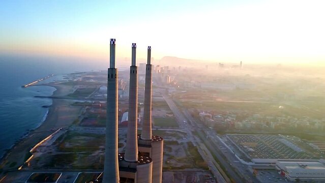 side travelling unique aerial drone image of Badalona three towers next to Barcelona at  sunset with unique lights skies, the beach, sea, town at the background  the buildings orbits in foreground 