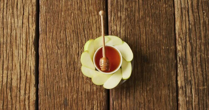 Video of honey in jar and apple slices lying on wooden surface
