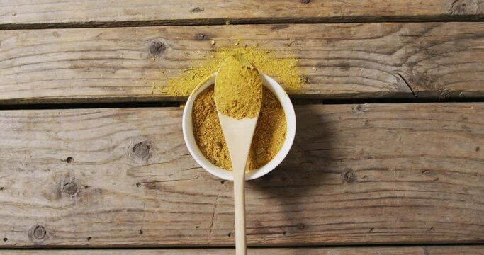 Video of spoon with tumeric seasoning lying on wooden surface