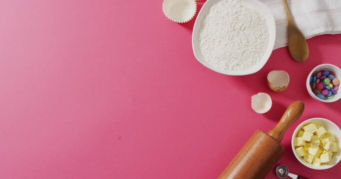 Video of baking ingredients and tools lying on pink surface with copy space