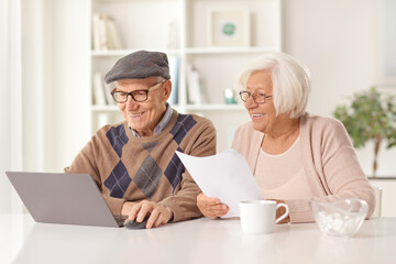 Happy elderly man and woman holding a document and looking at a laptop computer