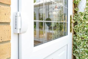 Shallow focus of door hinges seen on a newly installed double glazed PVC door which leads to a...
