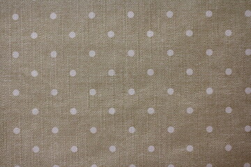 Beige fabric surface with small white circles. 