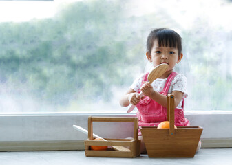 Asian girl Cute is enjoying toys on the floor in the living room by the window.