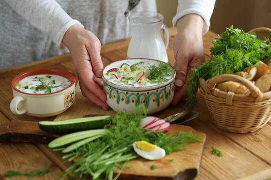 Women's hands hold a bowl with okroshka