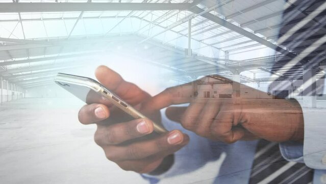 Animation of warehouse over african american man using smartphone