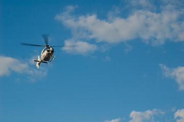 a police helicopter flies over a blue sky