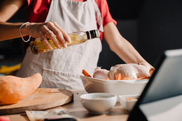 Young woman using tablet-computer while cooking in kitchen