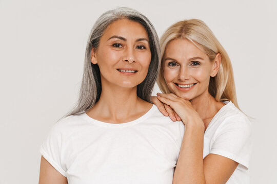 Mature happy multiracial women wearing t-shirts posing at camera