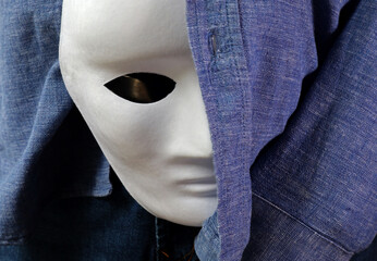 person in jeans with white theatrical mask