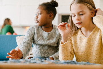 Adopted sisters solving puzzles sitting on couch