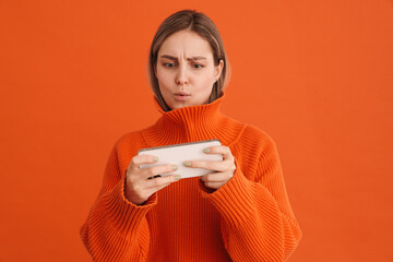 Young cute focused girl playing mobile game on her phone