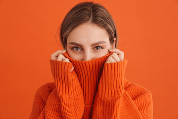Young cute girl hiding in sweaters neck