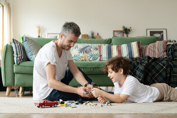 Father and son have fun playing together at home on a carpet in the living room