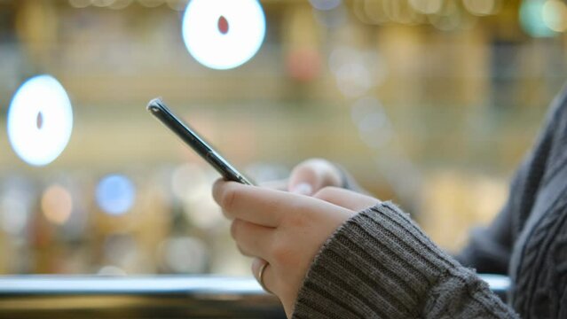 Shopping center. Moll. Finger of woman touching scroll page app on mobile phone. Browsing movie video in the internet library to watch film online.