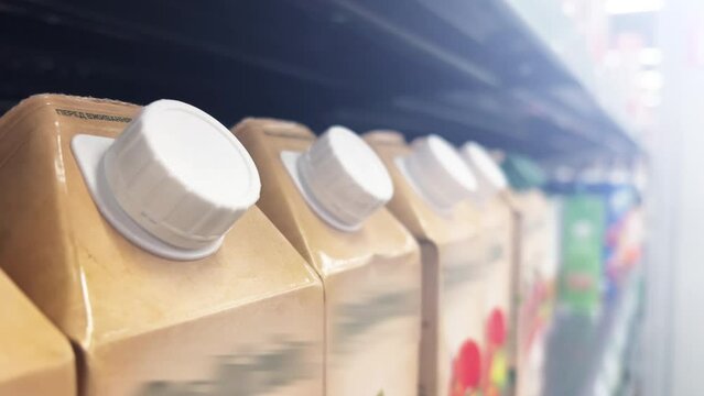 Fruit juice in carton cardboard boxes line up on the shelves of a supermarket or a grocery store. Close up shot