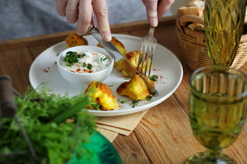 Women's hands with a knife and fork.Cauliflower in batter with white spicy sauce