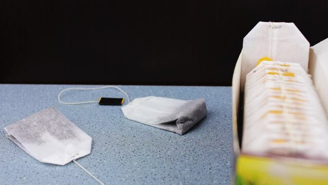 Tea bags on the background of tea packaging. Tea bag packaging on a black background. Assortment of tea bags.