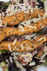 Food background. Caesar salad. Top view of fresh a salad with lettuce, parmesan cheese, bread croutons, fried chicken fingers breaded with sesame seeds and crispy bacon.	