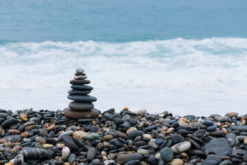stacked stones, tower or pyramid of stones on the beach, balance, Sea waves background （Hualien, Taiwan）