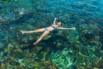 Young woman enjoys floating in a rocky tide pool in Tenerife, Canary Islands. The place is a puddle next to the sea called Charco de la Laja. 