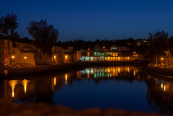 illuminated houses by a river at dusk in the Portuguese town of Tavira